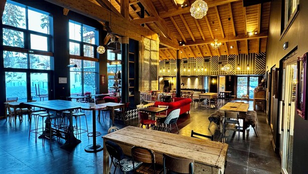 A spacious restaurant with high ceilings, large windows, and a variety of seating arrangements including tables and a red sofa. - Luxury penthouse with Mont Blanc views in Megève (Megève)