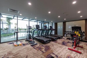 Ein Fitnessraum mit Laufbändern, Crosstrainern und einer Hantelbank.