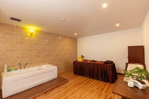 Un baño con una bañera grande, un tocador con espejo y una mesa con una planta.
