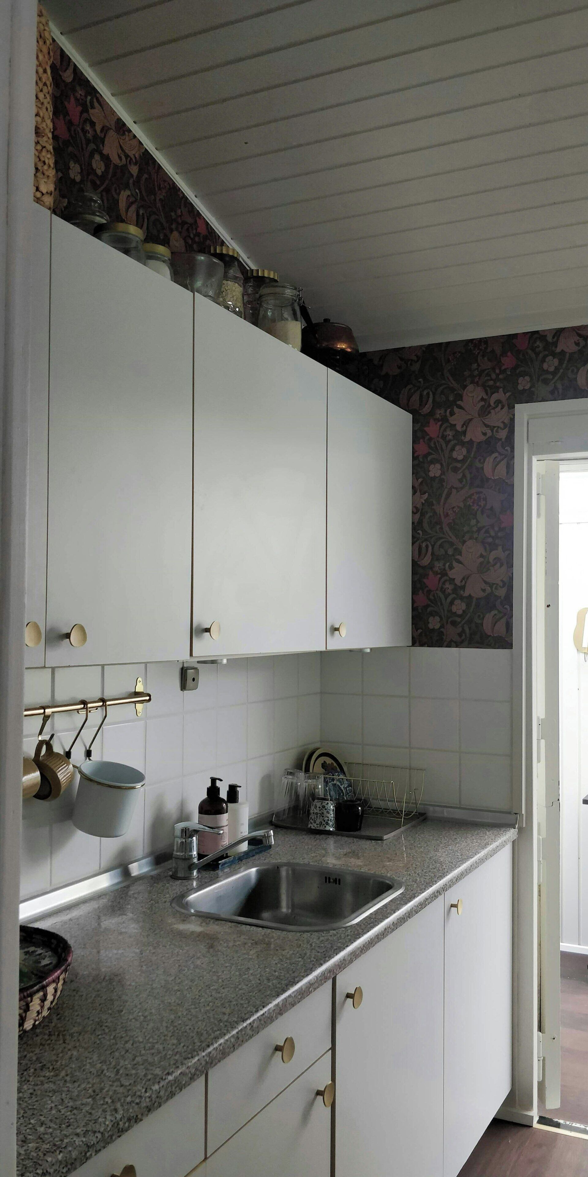 A kitchen with white cabinets, a granite countertop, a stainless steel sink, and a patterned backsplash.