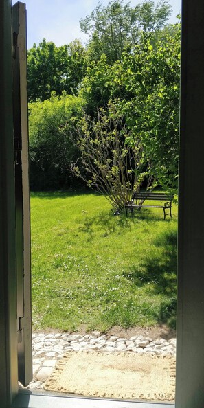 A view through an open door into a grassy outdoor area with a bench and a small tree. - Victorian summer house on beautiful natural plot (Rønde)