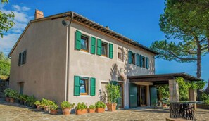 A two-story building with a stone facade, green shutters, and a covered outdoor seating area. - Hidden villa among olive trees in Tuscany (Palaia)