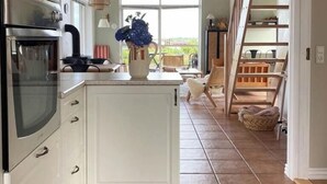 Une cuisine dotée d’un grand îlot central, d’un four encastré et offrant une vue sur l’extérieur par une fenêtre.