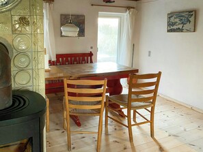 A dining area with a wooden table and chairs, a hanging light fixture, and a window with curtains. - Half-timbered house from 1800s near Præstø (Præstø)