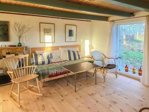 A cozy room with a bed, a rocking chair, a table, and a view of greenery outside. - Half-timbered house from 1800s near Præstø (Præstø)