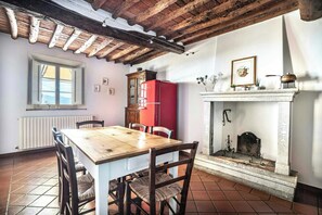 A dining area with a wooden table and chairs, a red refrigerator, a fireplace, and a window with a view. - Apartment by vineyard near Segromigno in Monte (Segromigno in Monte)