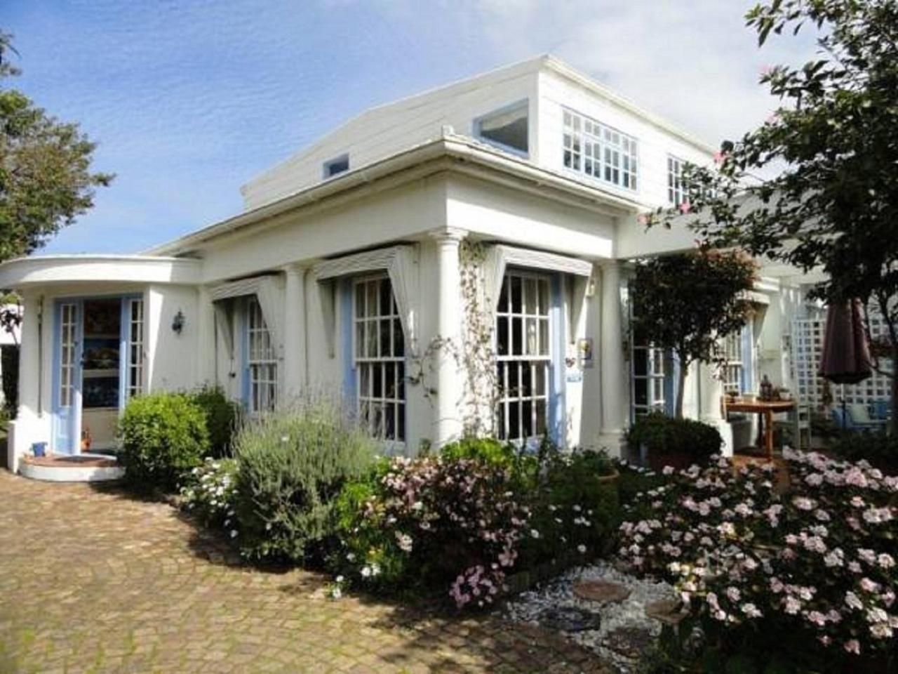A white building with a garden in front.