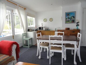 A kitchen with a dining table and chairs, a microwave, and a sink. - Eastbury Cottage (Hermanus)
