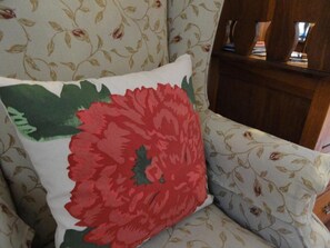 Ein Stuhl mit Stoffbezug mit Blumenmuster und einem großen, roten Kissen mit Blumen.