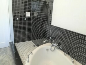 Ein Badezimmer mit einer weißen Badewanne, schwarzen Fliesenwänden und einem weißen Boden.