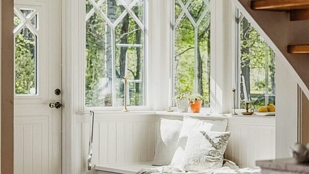 Una habitación con un banco incorporado, ventanas amplias y una escalera.