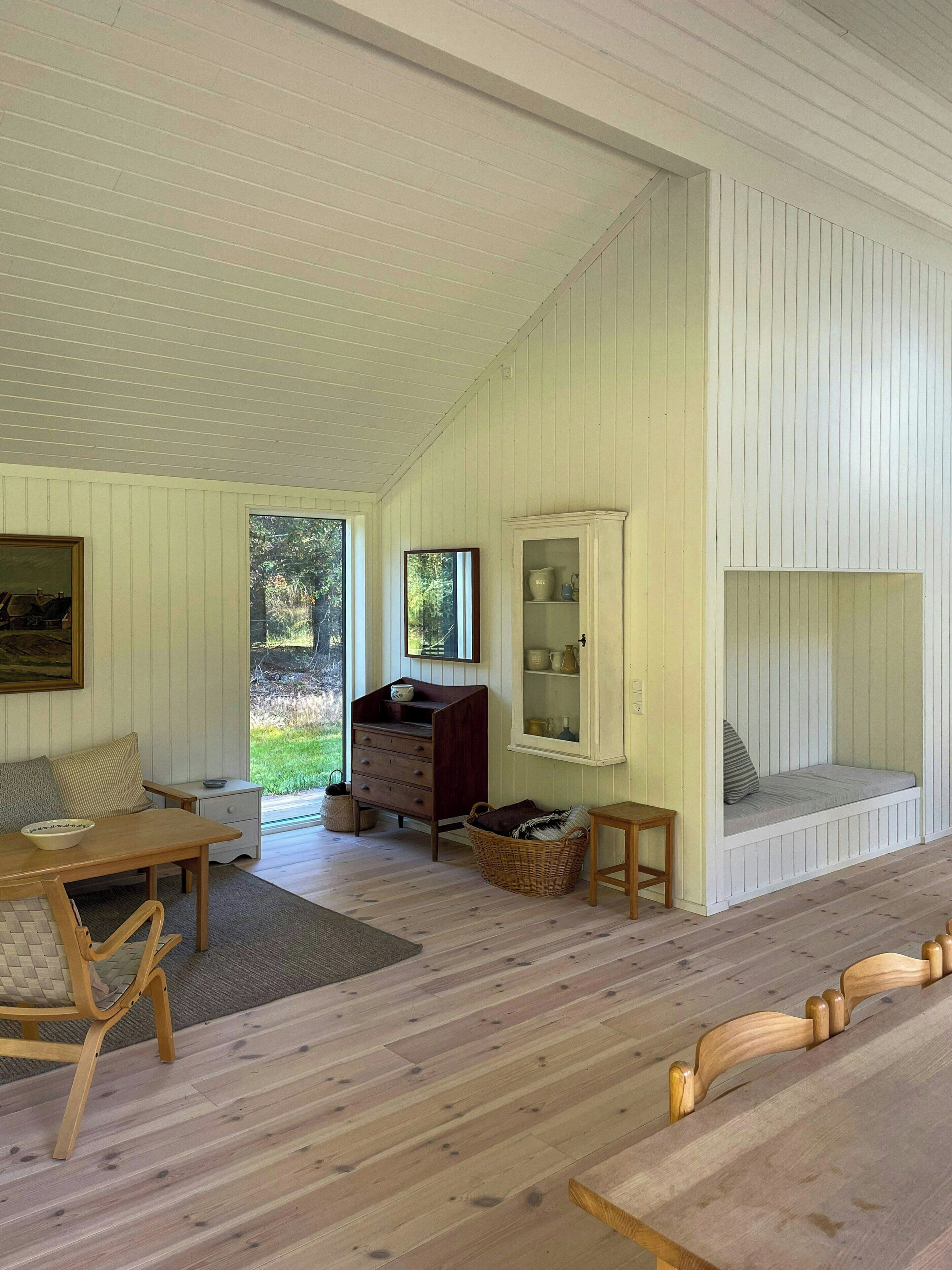 A room with a wooden table, a bench, a dresser, and a cabinet.