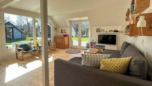 Un salon spacieux avec un grand canapé, un téléviseur et un plancher en bois.