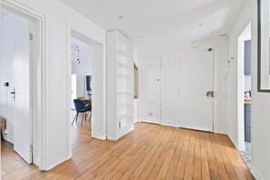 Ein geräumiges Zimmer mit Holzboden, weißen Wänden und einer Tür zu einem weiteren Raum.