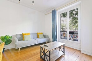 Ein Wohnzimmer mit einer Couch, einem Couchtisch, einem großen Fenster mit Blick und einer Pflanze.