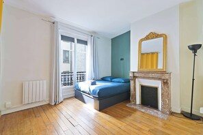 Ein Schlafzimmer mit Bett, Kamin, Fenster mit Vorhängen und Heizkörper.