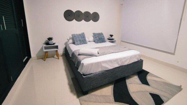 A bedroom with a bed, bedside tables, a rug, and a wall-mounted decoration.