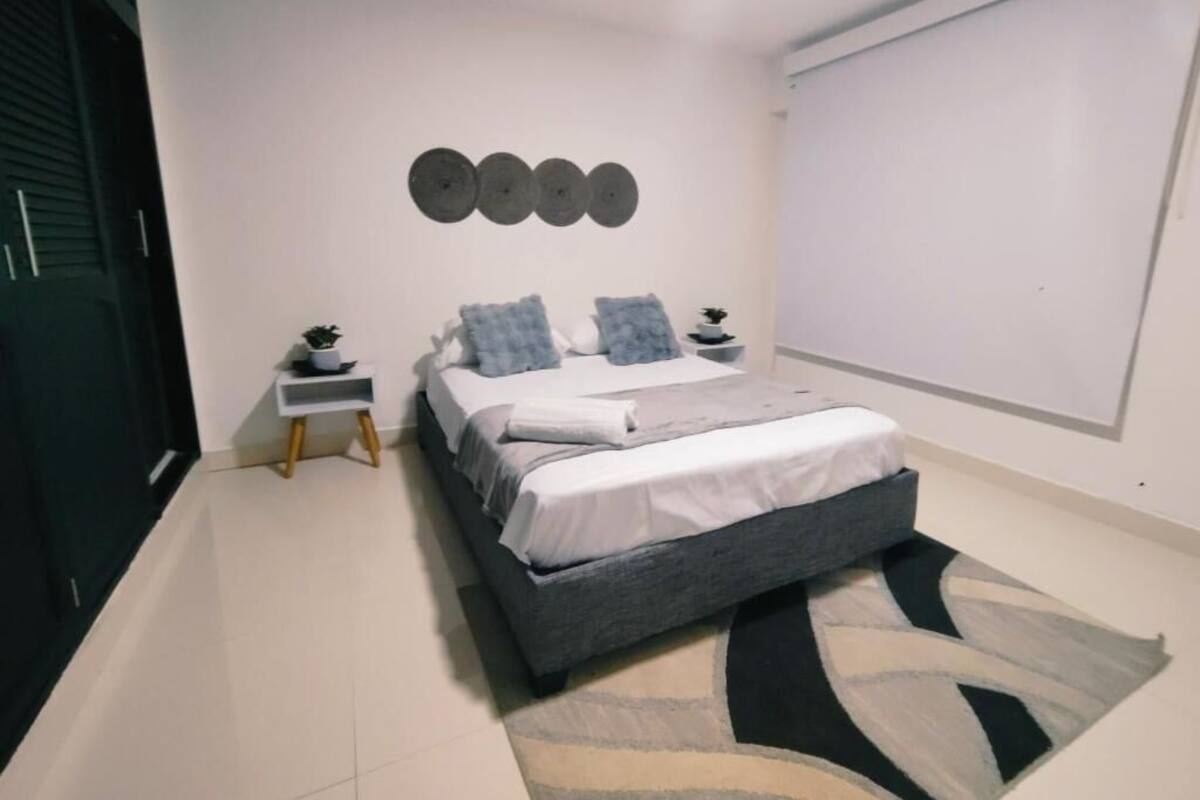 A bedroom with a bed, bedside tables, a rug, and a wall-mounted decoration.