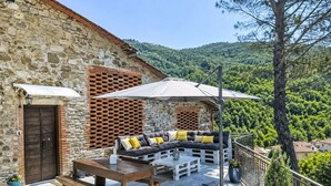 An outdoor seating area with a stone wall, a wooden table, and a bench. - La Casa di Fiore by Interhome (Poppi)