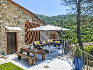 An outdoor seating area with a stone wall, a wooden table, and a bench. - La Casa di Fiore by Interhome (Poppi)