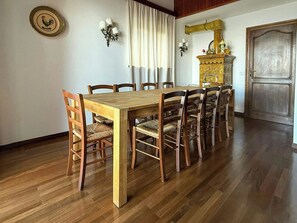 Ein Esszimmer mit Holztisch und -stühlen, einer Chandelieber und einem dekorativen Schrank.