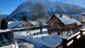 Un village de montagne aux maisons en bois, sous un ciel dégagé, et dont le sol est recouvert de neige.