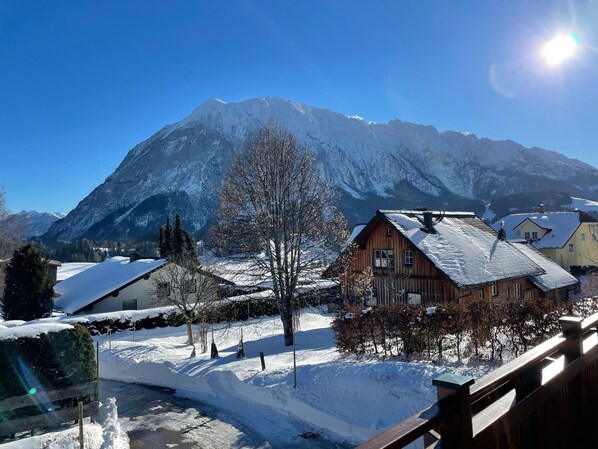 Een bergdorpslandschap met houten huizen, een heldere lucht en besneeuwde grond.