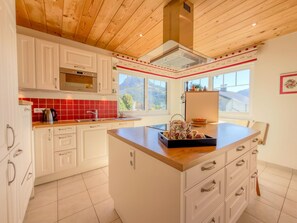 A kitchen with white cabinets, a red-tiled backsplash, a built-in oven, and a large window offering a view of the outdoors.