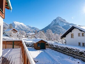Eine verschneite Berglandschaft mit einer Holzhütte und einem weißen Gebäude mit vielen Fenstern.