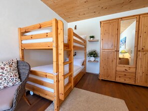 Une chambre avec un lit superposé, des murs en bois et une armoire.