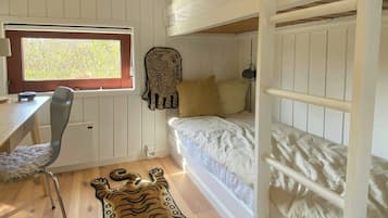 Une chambre avec un lit superposé, un bureau avec une chaise, une fenêtre et un tapis à motifs de tigre sur le sol.