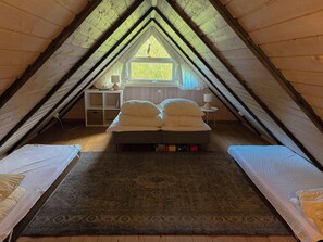 An attic bedroom with a bed, a small table, and a window.