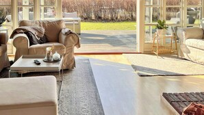 A spacious living room with a large window, a sofa, a coffee table, and a rug.