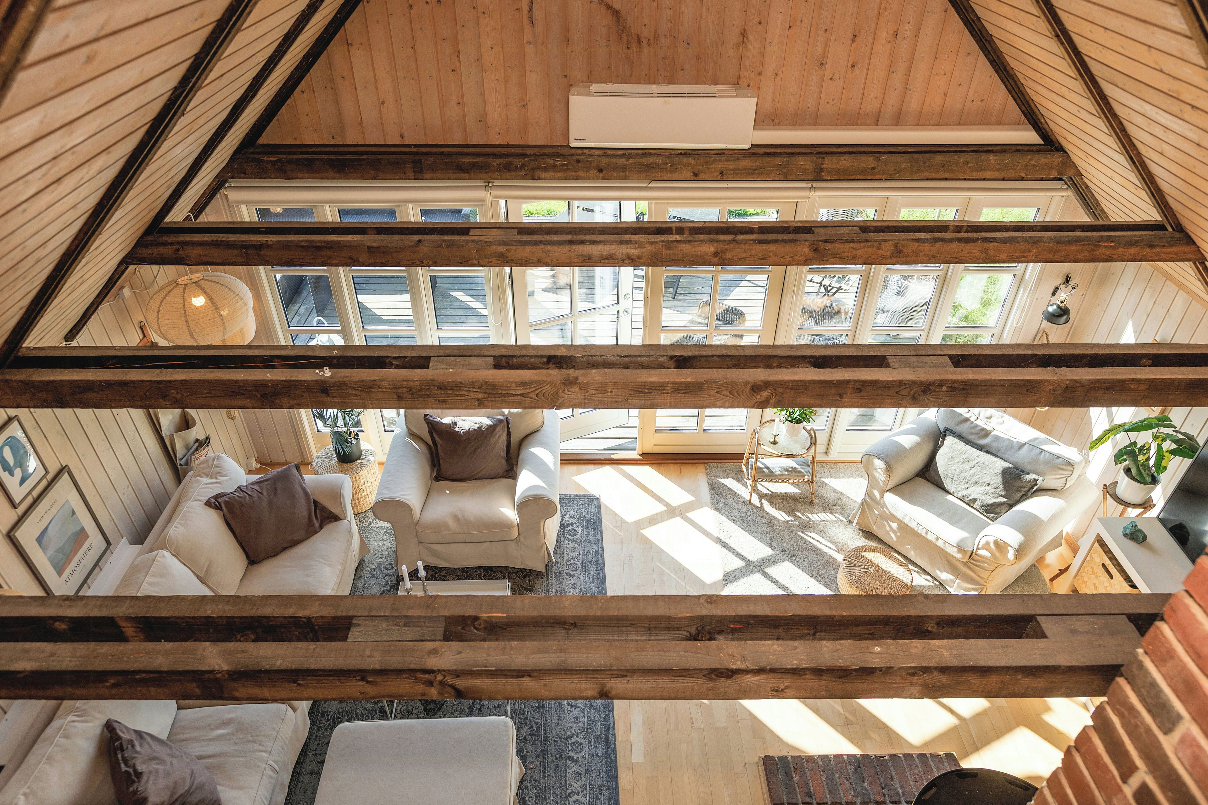 A high-ceilinged room with a sloped roof, large windows, and a view of the outdoors.