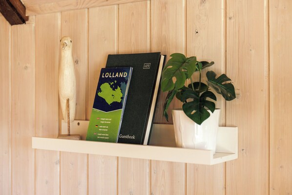 Une étagère avec un livre d’or, une carte de l’île de Lolland et une plante.