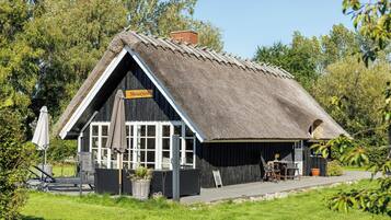 En traditionel bygning med stråtækt tag og et skilt, der siger 'Hostaken'.