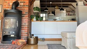 A rustic kitchen with a brick stove, wooden beams, and a white countertop.