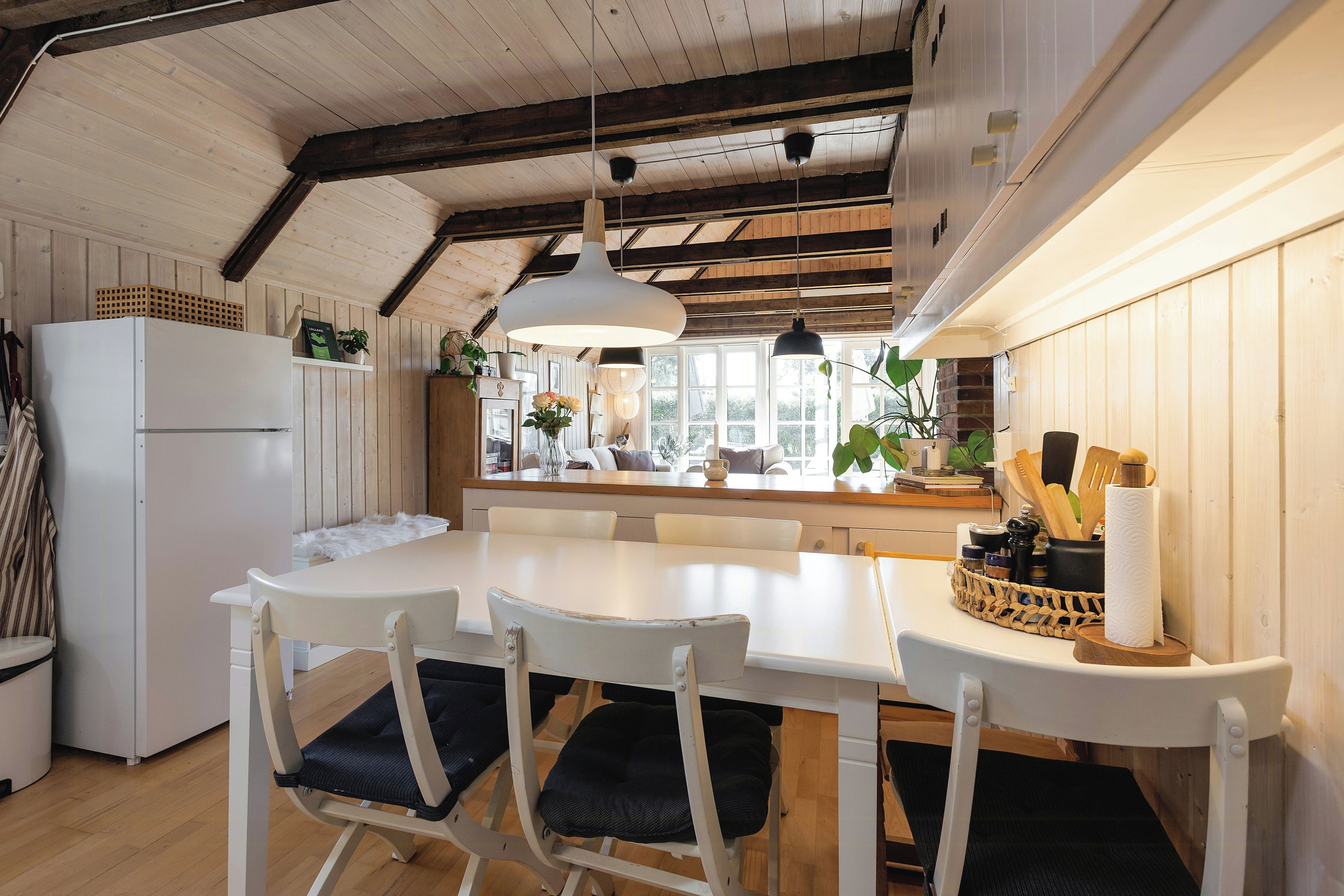 Una cocina moderna con una mesa blanca, sillas y un refrigerador.