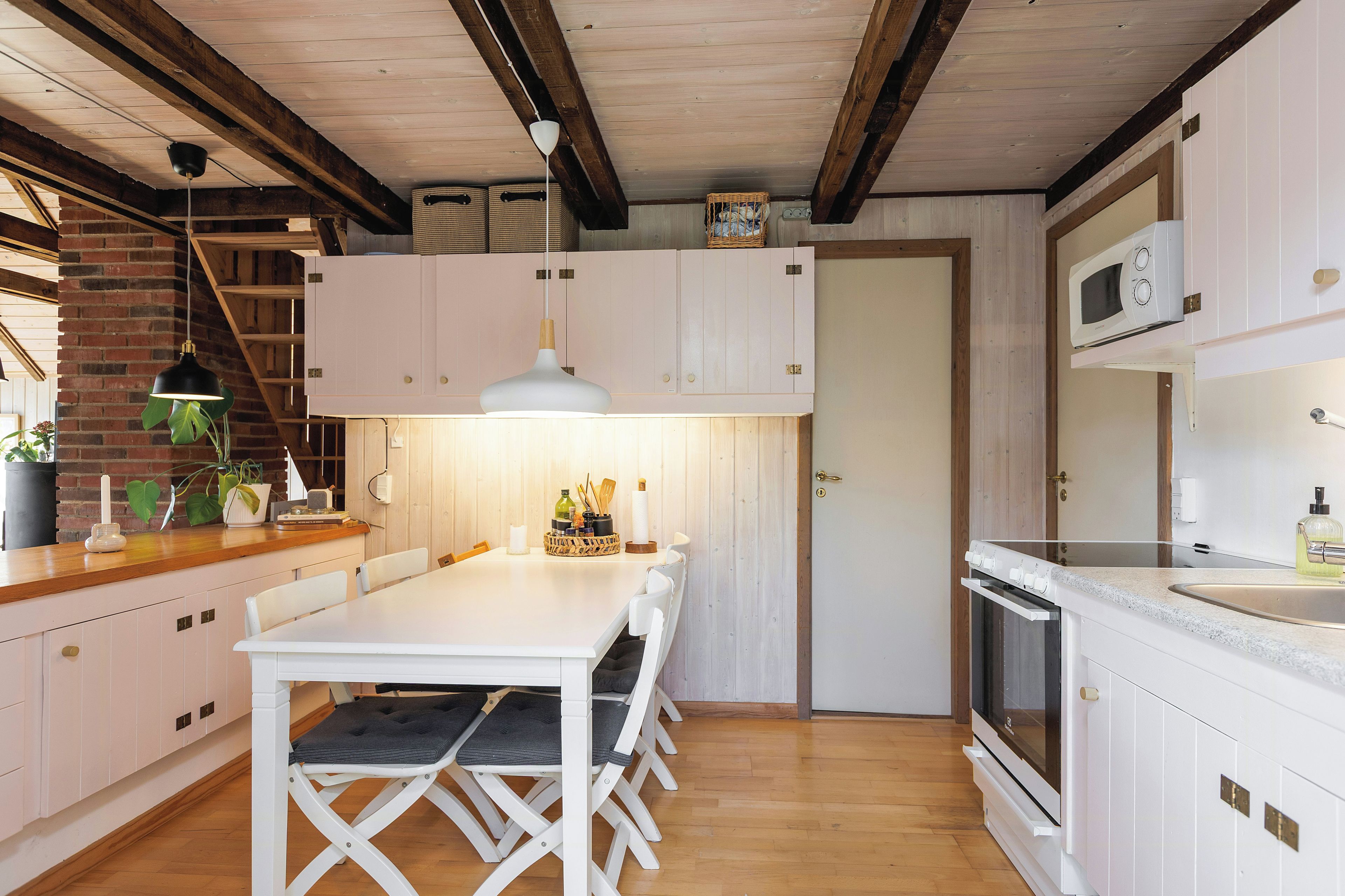 Una cocina moderna con armarios blancos, una mesa de comedor de madera y un horno empotrado.