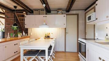 Una cocina moderna con armarios blancos, una mesa de comedor de madera y un horno empotrado.