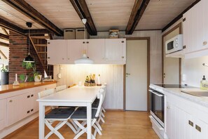 A modern kitchen with white cabinetry, a wooden dining table, and a built-in oven.