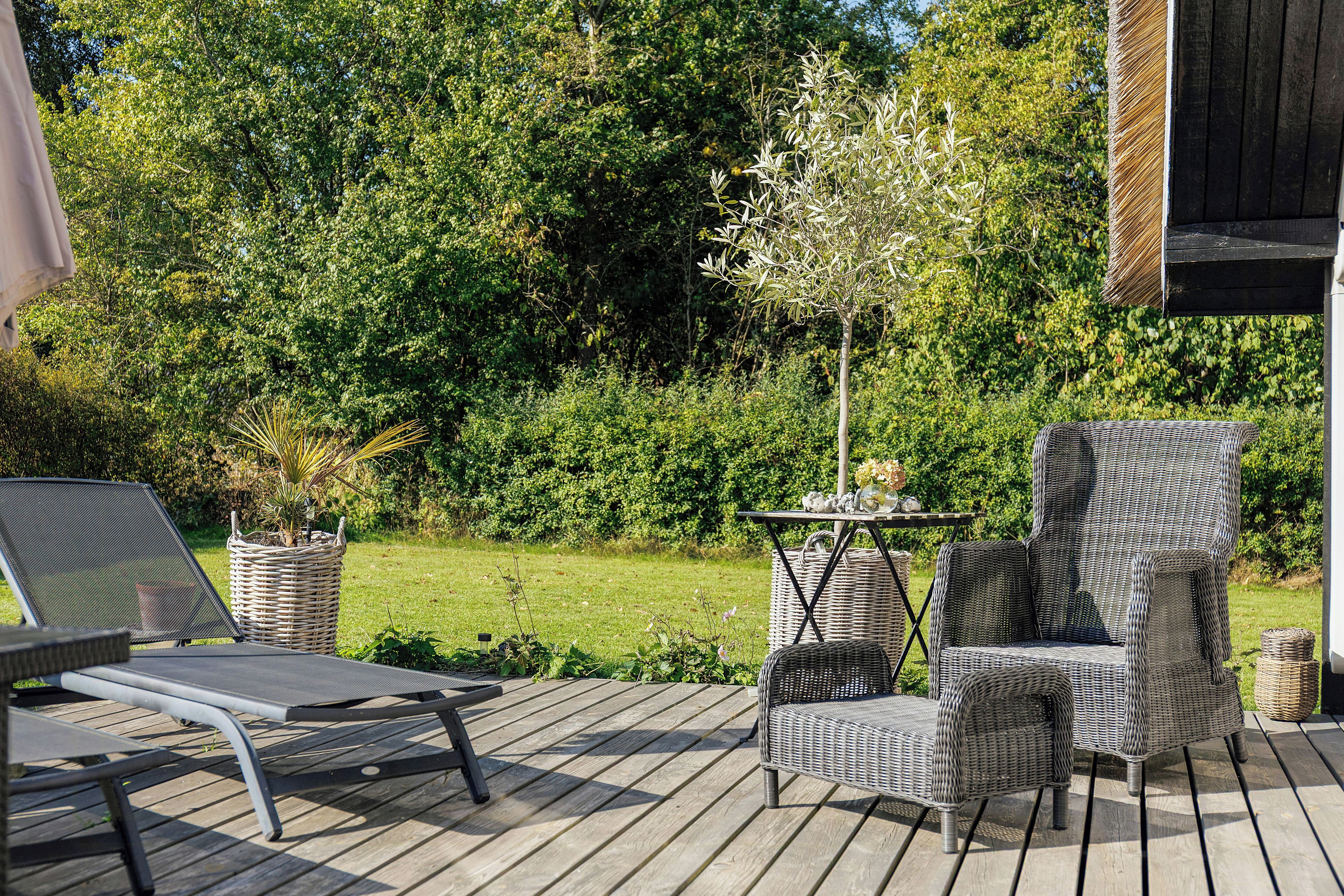 Una terraza de madera con mobiliario exterior, incluyendo una silla y una mesa.