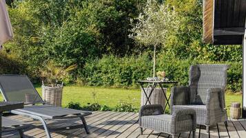 Una terraza de madera con mobiliario exterior, incluyendo una silla y una mesa.
