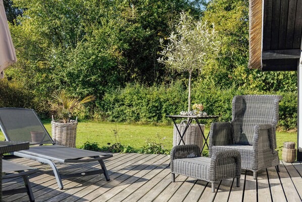 A wooden deck with outdoor furniture, including a chair and a table. - Thatched cottage with wildlife near Kramnitze (Dannemare)