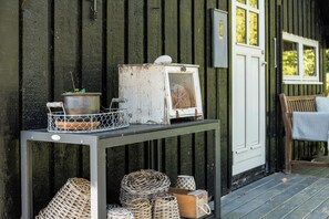 A rustic outdoor setting with a metal table holding a bird feeder, a potted plant, and wicker baskets. - Thatched cottage with wildlife near Kramnitze (Dannemare)