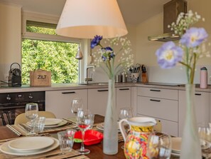 A modern kitchen with a dining area set for a meal, a window with greenery outside, and a bag labeled 'ZILT VAKANTIES'. - Spacious holiday home near Veerse Meer (Kamperland)