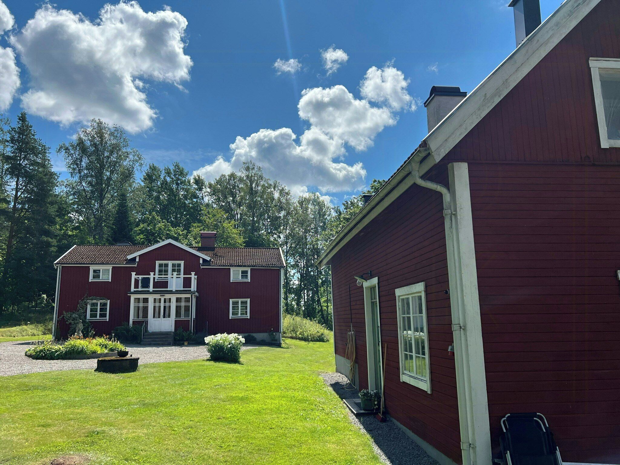 Punainen puutalo, jossa on kuisti, sorapäällysteinen ajotie ja hyvin hoidettu nurmikko.