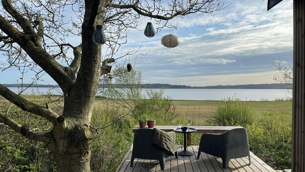Een houten terras met een tafel en stoelen met uitzicht op een meer.