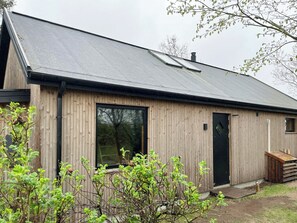 A wooden building with a large window, a door, and a small window. - Modern wooden house near Halkær bredning (nibe)