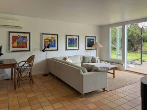 Een woonkamer met een bank, een eettafel, een lamp en kunst aan de muur.